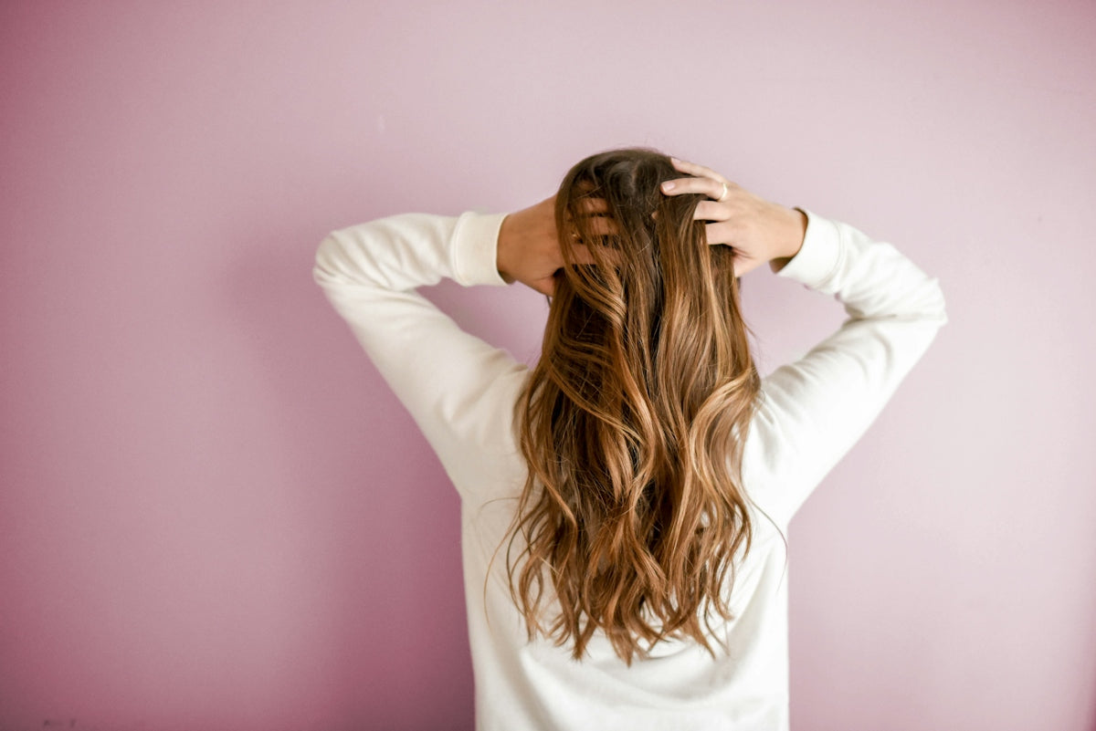Frau mit langem Haar vor einer rosa Wand