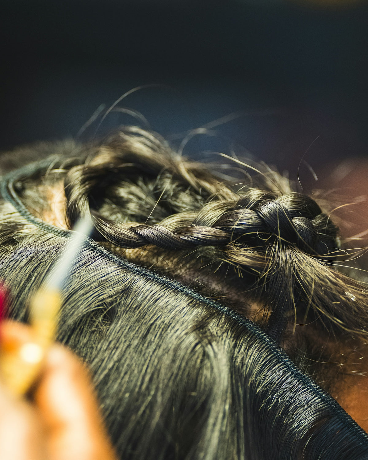 Close-up of a person braiding dark hair.